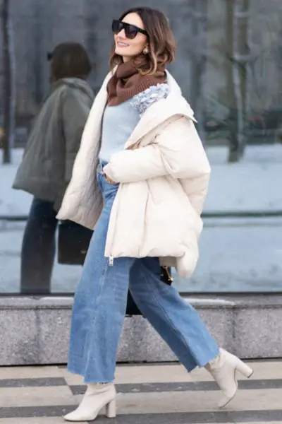 A woman wears coat with sweater, wide leg jeans and cowboy boots