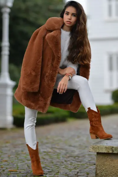 A woman wears fur coat with white outfit and brown cowboy boots 2