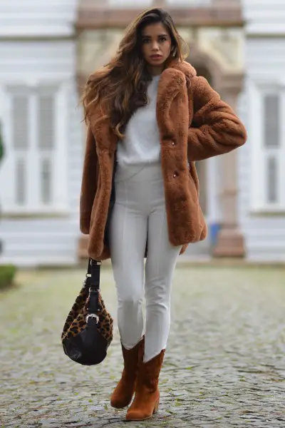 A woman wears fur coat with white outfit and brown cowboy boots
