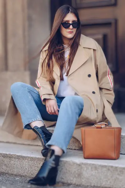 A woman wears jeans, blazer, white top with black ankle cowboy boots, sunglasses and tote bag