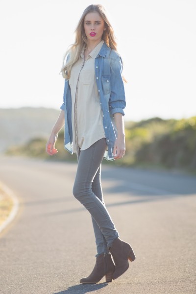 A woman wears jeans with ankle boots, white shirt and denim coat