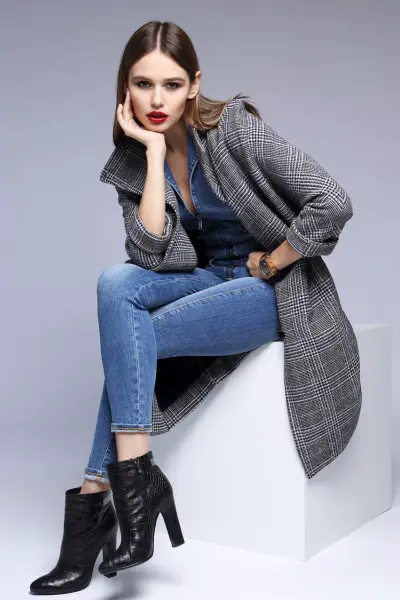 A woman wears jeans with black ankle boots and coat