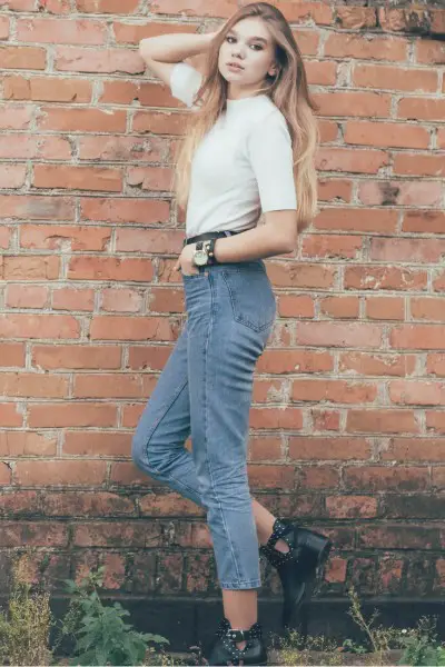 A woman wears jeans with black ankle boots and white tee