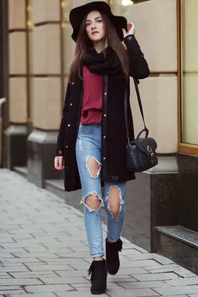 A woman wears jeans with black suede boots, red top and sweater