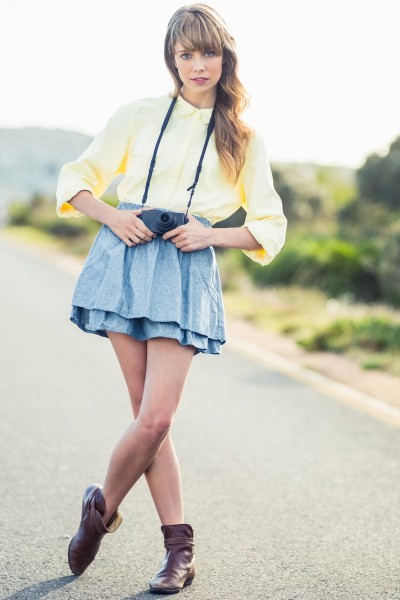 A woman wears mini skirt, blouse and ankle cowboy boots