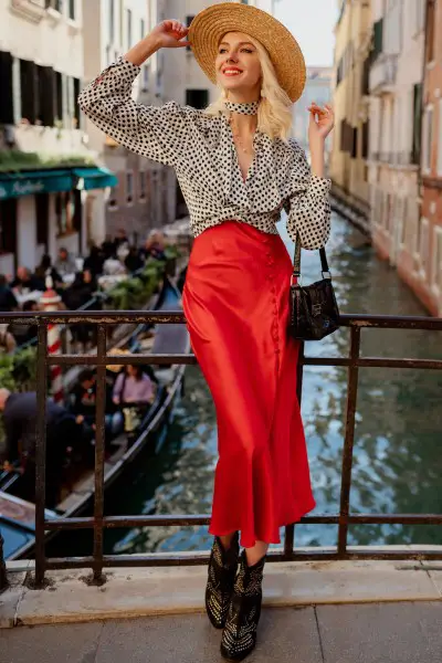 A woman wears red skirt with cowboy boots and dotted blouse and stand on the bridge