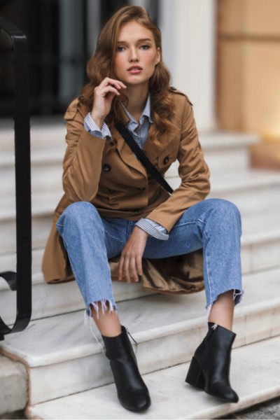 A woman wears ripped hem jeans with cowboy boots and coat