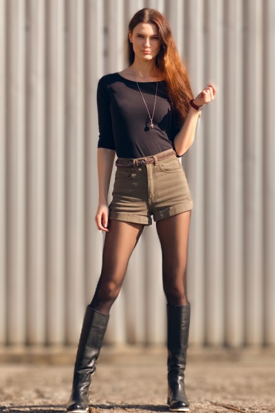 A woman wears shorts jeans with tight top and black cowboy boots