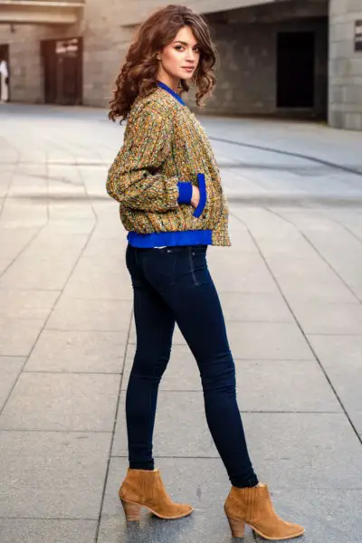 A woman wears skinny jeans with suede boots and bomber jacket