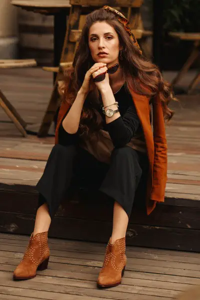 A woman wears suede boots with black outfit and brown coat