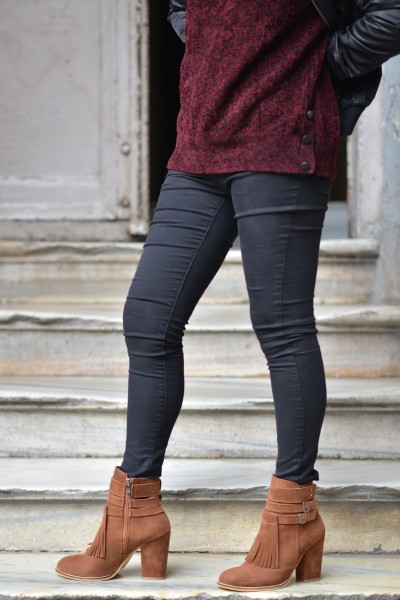 A woman wears suede boots with leggings and red top