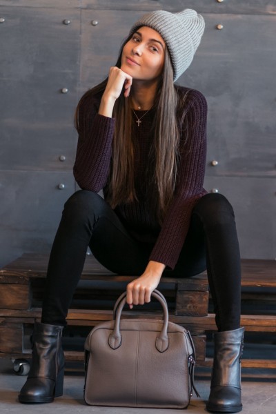 A woman wears sweater and black cowboy boots