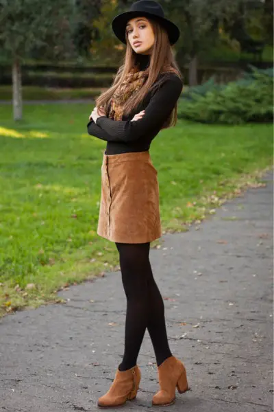 A woman wears tight top with suede mini skirt and tights and brown cowboy boots