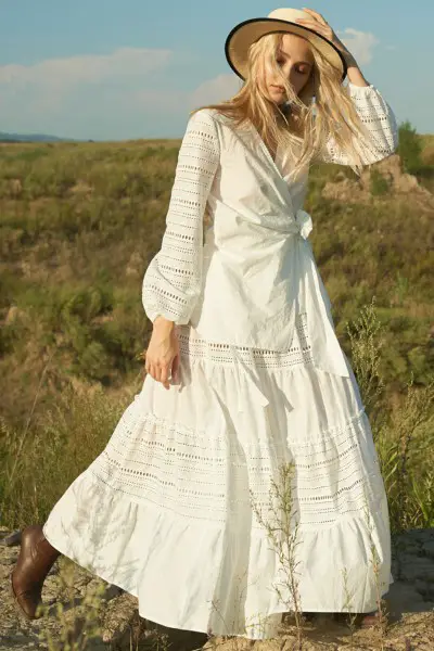 A woman wear white top, white skirt and cowboy boots