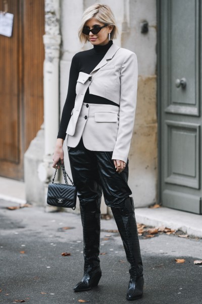 A woman wears a stylish suit blazer, leather trousers and black cowboy boots