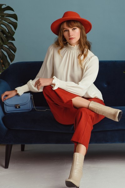 A woman wears ankle boots with red trouser and white blouse