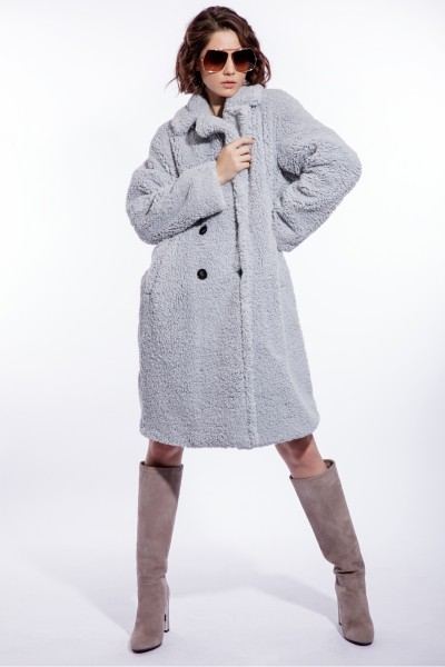 A woman wears beige cowboy boots, grey boots and fur dress coat