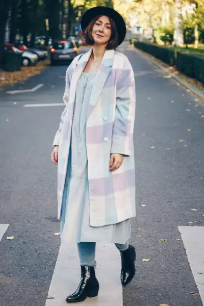 A woman wears black boots, jeans, dress and coat