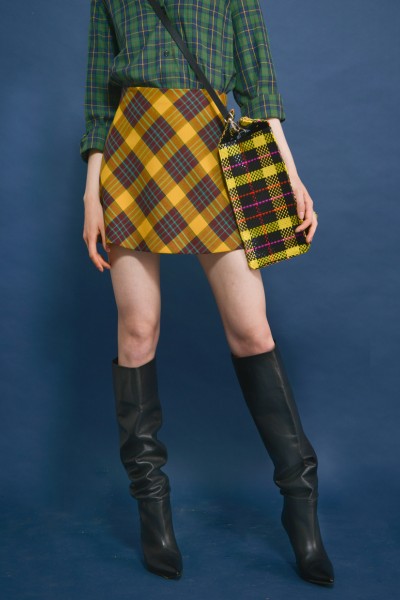 A woman wears black cowboy boots, plaid skirt and top