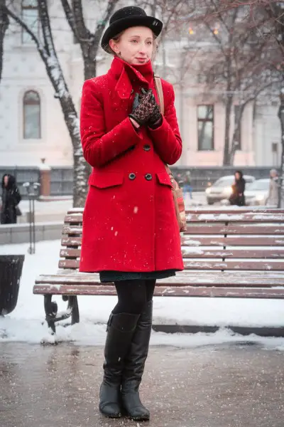 A woman wears black cowboy boots, red trench coat and leggings