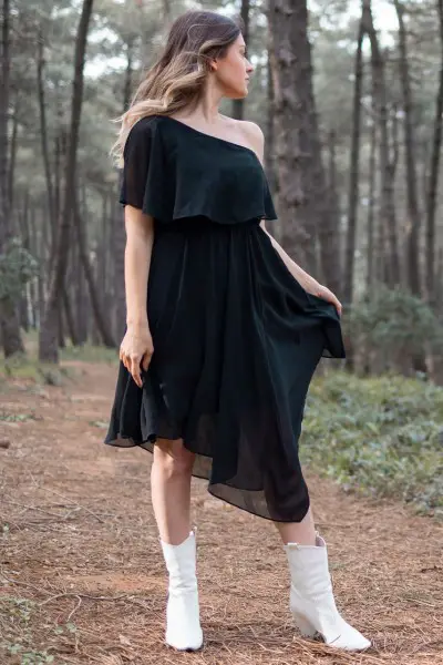 A woman wears black dress with white cowboy boots