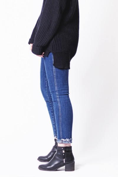 A woman wears black sweater, jeans and black ankle boots