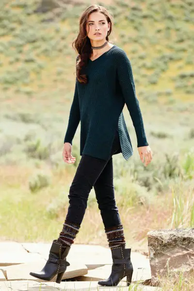 A woman wears boots, black jeans and green sweater