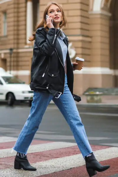 A woman wears boots, turtleneck, jeans and leather jacket