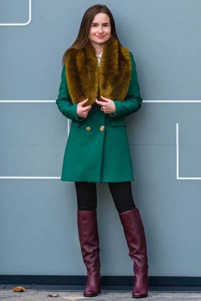 A woman wears brown cowboy boots, black legging and teal coat