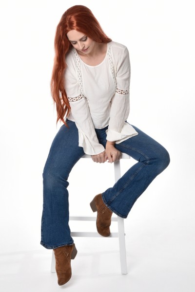 A woman wears brown cowboy boots with blue jeans and long sleeves white top