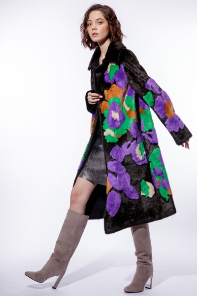 A woman wears colorful coat with pencil dress and cowboy boots