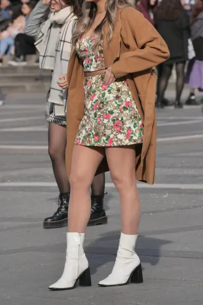 A woman wears cowboy boots with floral mini dress
