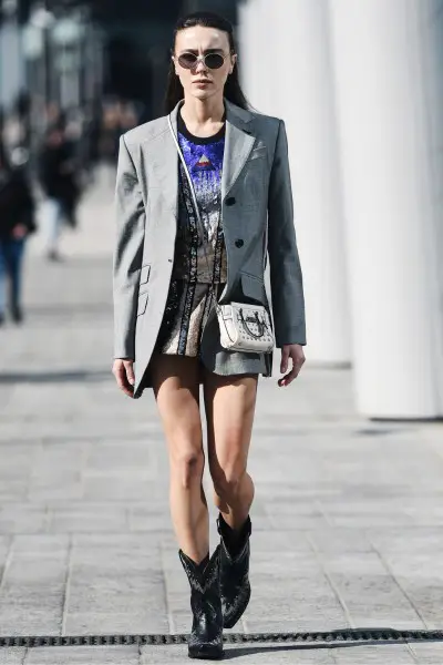 A woman wears cowboy boots with mini dress and blazer