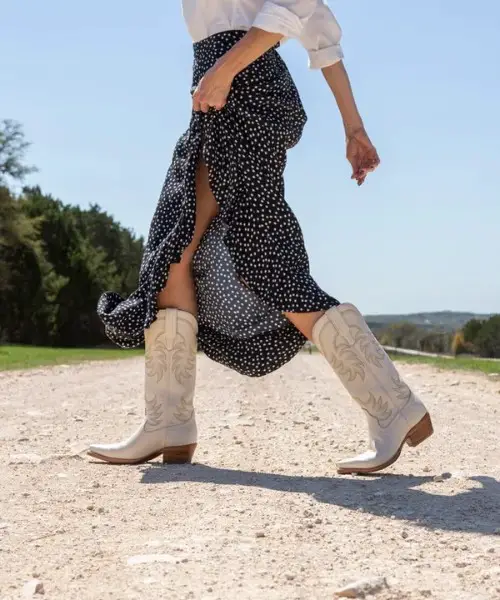 A woman wears dotted skirt, blouse and The Annie Boots