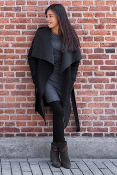 A woman wears grey dress, black leggings and boots