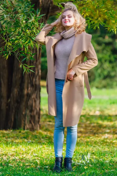 A woman wears jeans, short black cowboy boots, blazer and turtleneck.