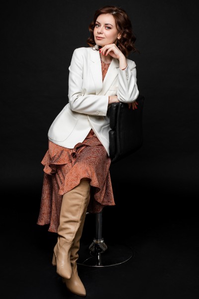 A woman wears orange long dress with cowboy boots and suit blazer