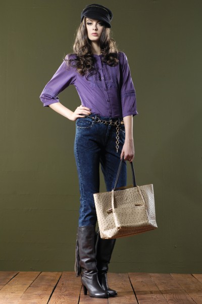 A woman wears purple top, jeans and brown boots.