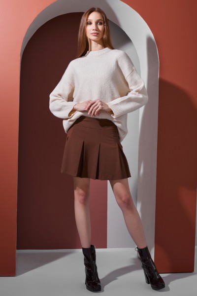 A woman wears skirt, sweater and ankle boots