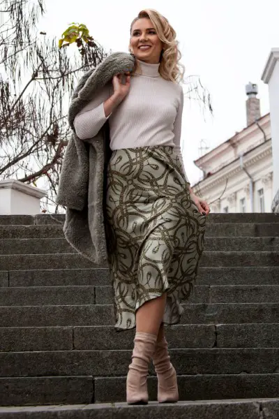 A woman wears textured skirt, ankle boots, sweater and fur coat
