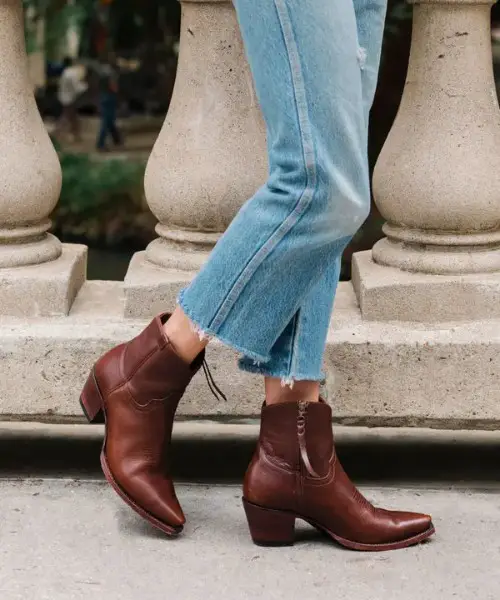 A woman wears the daisy boots with jeans