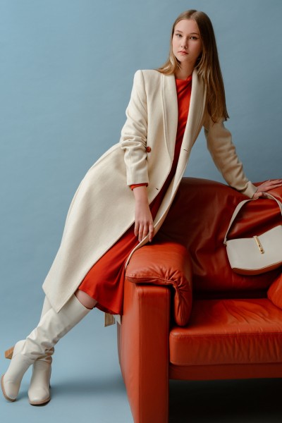 A woman wears white cowboy boots with white trench coat and red cowboy boots
