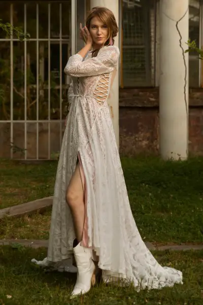 A woman wears white wedding dress with white cowboy boots