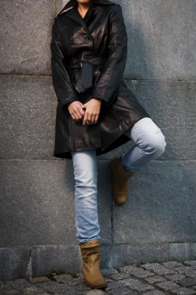 A woman weas brown cowboy boots, fade jeans and black leather blazer