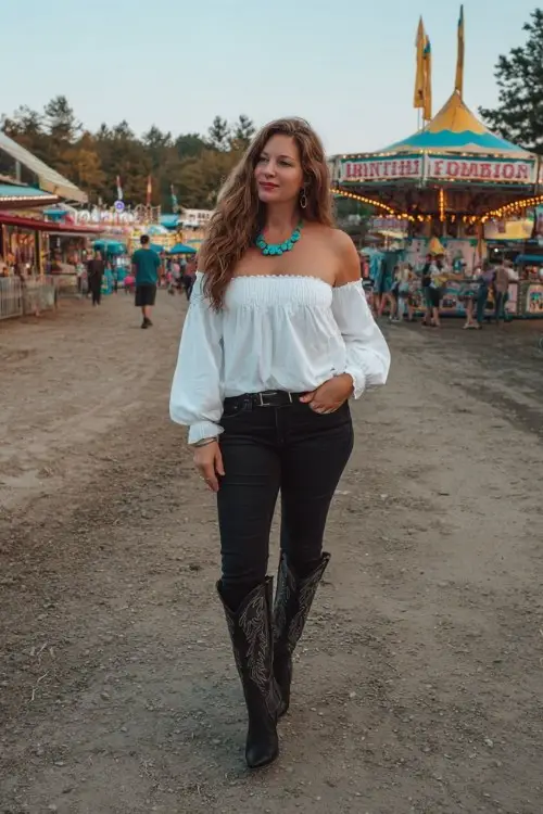 A curvy woman wears skinny jeans with black tall cowboy boots, a white off-shoulder blouse, and turquoise jewelry
