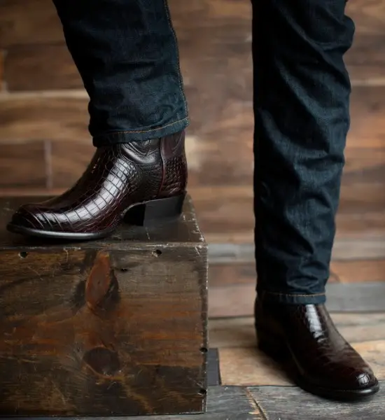 A man wears jeans with exotic caiman cowboy boots