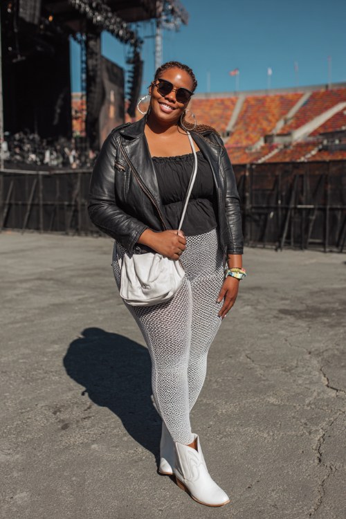 A plus-size woman wears white ankle cowboy boots with faux-leather leggings, a fitted off-shoulder knit top and cropped leather jacket, finished with a mini shoulder bag