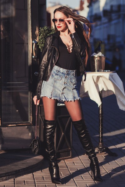 A woman wears a denim skirt with black cowboy boots