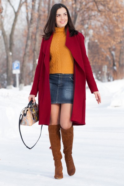 A woman wears a denim skirt with brown cowboy boots