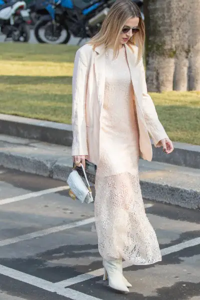 A woman wears ankle white cowboy boots with white dress and a blazer